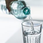 A bottle of water being poured into a glass