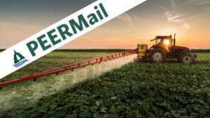 tractor spraying pesticides on agricultural field