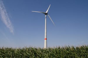 Wind turbine with blue sky in background and grass in foreground